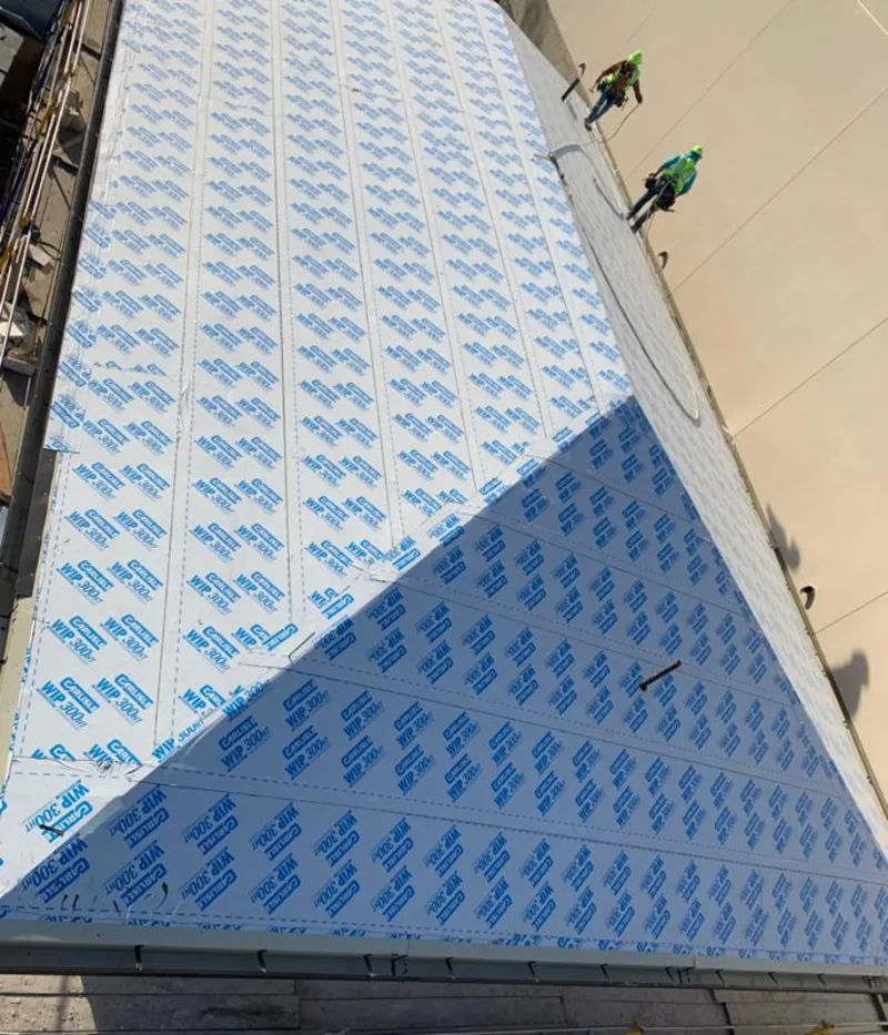 Professional roofers installing underlayment on a metal roof in Muskego